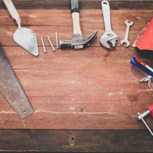 Flat lay of various workshop tools on a rustic wooden table, showcasing DIY essentials.