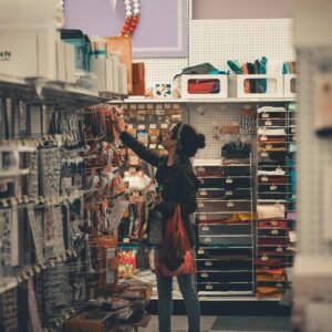 Woman reaching for items in a busy craft store aisle, exploring various art supplies.